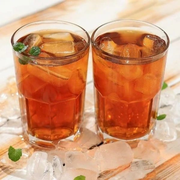 Two glasses of iced tea with mint leaves and ice cubes on a wooden surface.